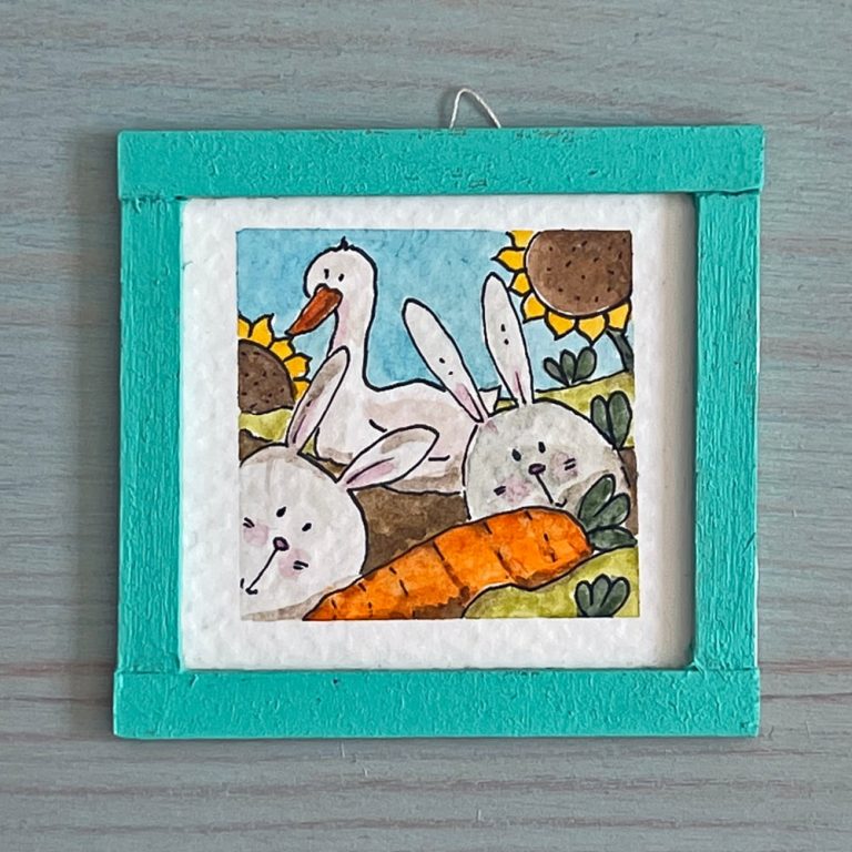 A watercolor mini painting depicting two curious bunnies and a carrot on the front, and a goose and some sunflowers on the back.
